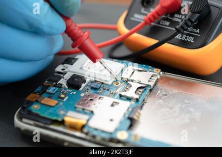 Technician repairing inside of mobile phone by soldering iron. Integrated Circuit. the concept of data, hardware, technology. Stock Photo