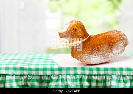 Easter Card Template. A traditional Easter lamb cake on a white plate on a green checked tablecloth against a blurred window background. Space for design. Stock Photo