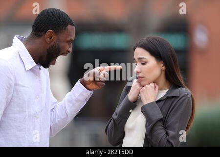 Angry man scolding and accusing to a scared woman Stock Photo