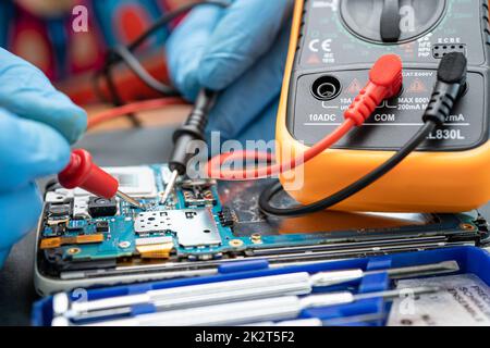 Technician repairing inside of mobile phone by soldering iron. Integrated Circuit. the concept of data, hardware, technology. Stock Photo