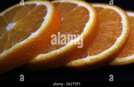 Close-up of orange slices on a black background. Stock Photo