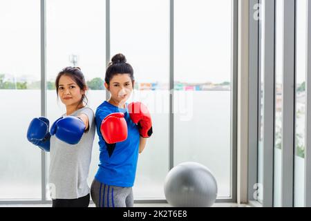 adult and young woman smiling sports fitness boxer wearing gloves practicing kick on boxing Stock Photo