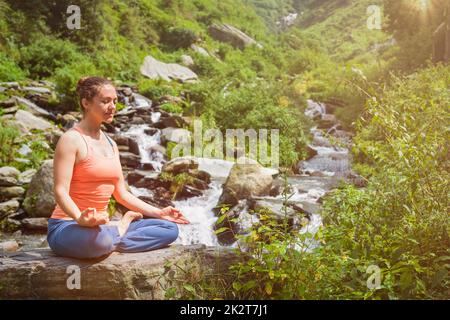 Woman in Padmasana outdoors Stock Photo