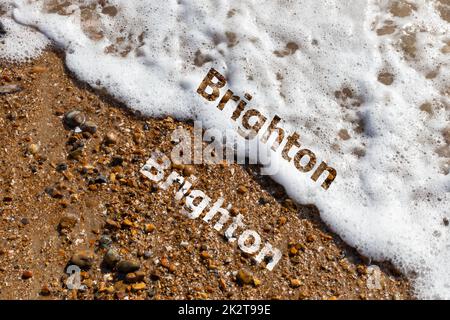 Brighton text cut out on both pebble beach and lapping waves Stock Photo