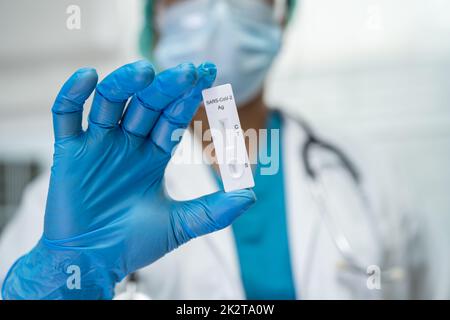 Asian doctor in PPE suit show positive test result with Saliva Antigen Test Kit for check Covid-19 coronavirus in hospital. Stock Photo