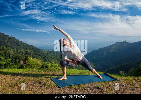Woman practices yoga asana Utthita Parsvakonasana outdoors Stock Photo
