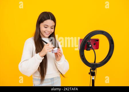 Beauty blog, presenting makeup cosmetics powder and brush. Teen girl speaking in front of camera for vlog. Teenager working as blogger, recording Stock Photo