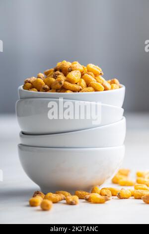 Roasted salted corn snack in bowl on white table. Stock Photo