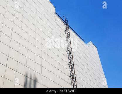 Outdoor fire escape on the wall of an office or industrial building. Bottom-up view. Fire escape on the facade of the building for access to the roof in emergency situations Stock Photo