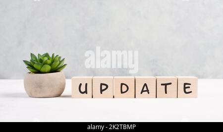 The words update is standing on wooden cubes, progress in business, desk in an office, copy space for text, catus plant Stock Photo