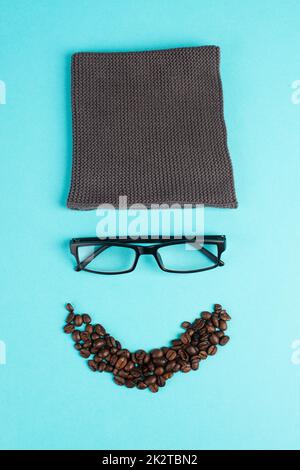 Human face made with a wool hat, glasses and coffee beans as a beard, funny minimalist portrait, eco freak lifestyle, having breakfast, taking a break Stock Photo