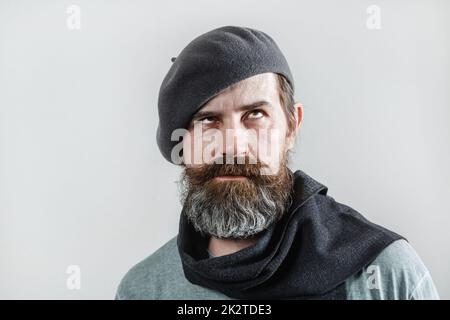 Bearded man in gray beret with scarf. Studio portrait on a light background. Stock Photo