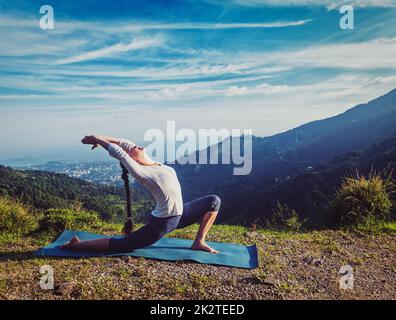 Sporty fit woman practices yoga Anjaneyasana in mountains Stock Photo