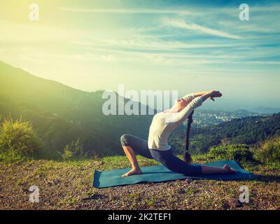 Sporty fit woman practices yoga Anjaneyasana in mountains Stock Photo
