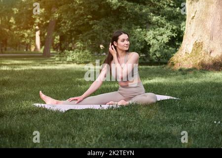 A young woman practices yoga in a city park on a warm summer day. Stock Photo