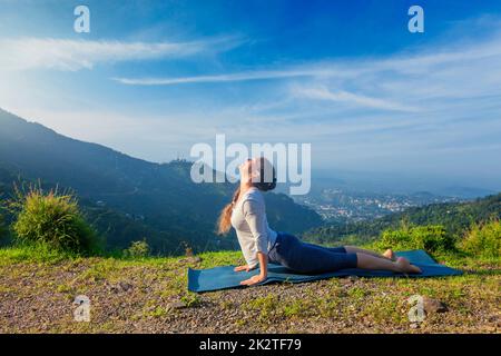 Woman practices yoga asana Urdhva Mukha Svanasana outdoors Stock Photo