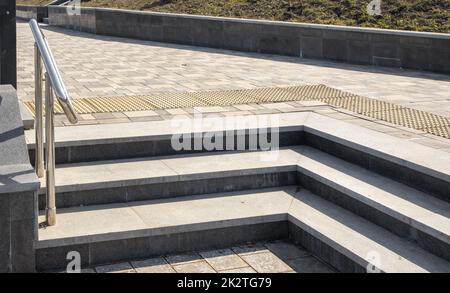 Close-up of granite stone steps located at an angle, in a metal railing, outdoors, in a city park Stock Photo