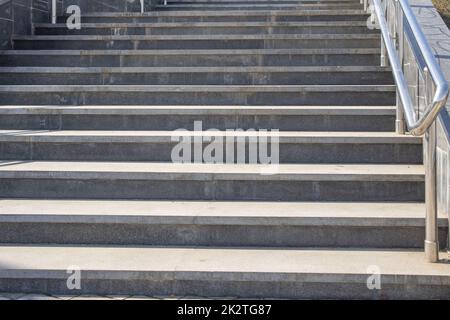 Outdoor concrete steps on a modern city staircase with metal railings on a sunny day, outdoors, bottom view Stock Photo