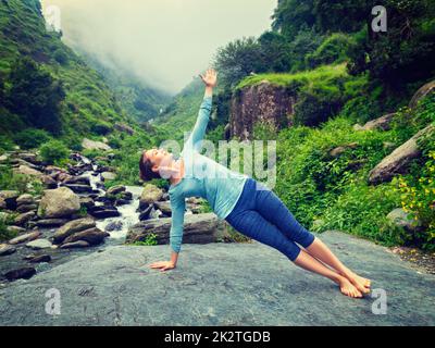 Woman doing yoga asana Vasisthasana - side plank pose outdoors Stock Photo