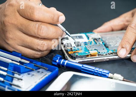 Technician repairing inside of mobile phone by soldering iron. Integrated Circuit. the concept of data, hardware, technology. Stock Photo