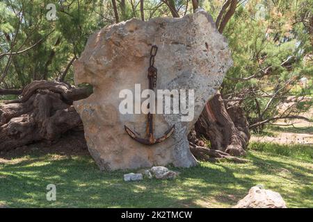 Old rusted ship's anchor on a stone. Stock Photo