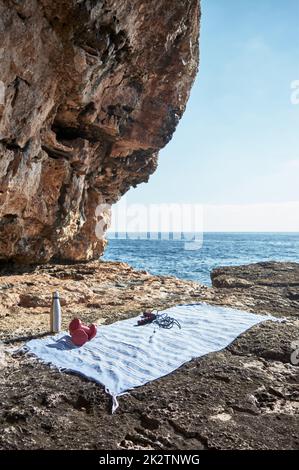 Fitness and sports concept background. Getting ready. Towel, jump rope, dumbbell and bottle of water, by the sea on a sunny winter day, with beautiful blue sky Stock Photo