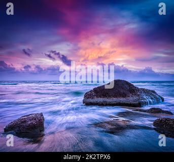 Waves and rocks on beach of sunset Stock Photo