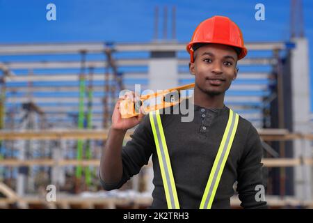 construction site worker holding level tool and wearing red security hat helmet safety equipment Stock Photo