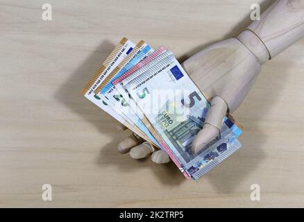 Give away money. A wooden hand and euro bills Stock Photo