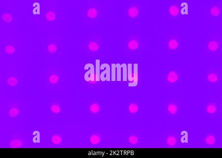 Abstract purple paper background with holes arranged in a row and glowing with neon color Stock Photo