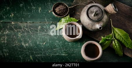 Vintage green asian tea pot with two mugs on rustic background. Stock Photo
