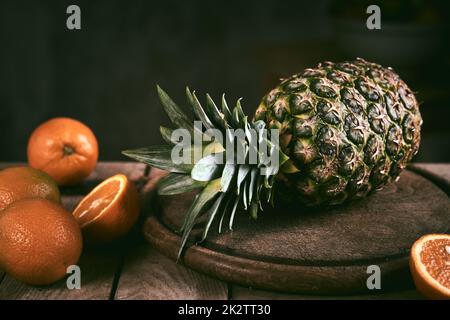 Pineapple and oranges on wooden table Stock Photo