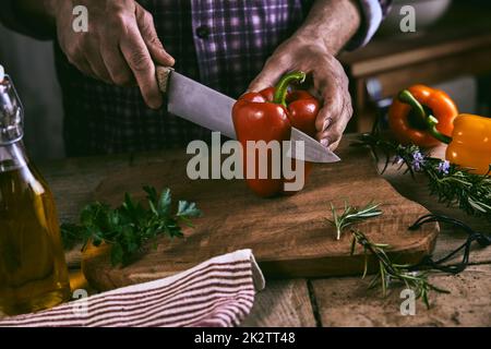 Crop faceless chef cutting bell pepper during dinner preparation Stock Photo