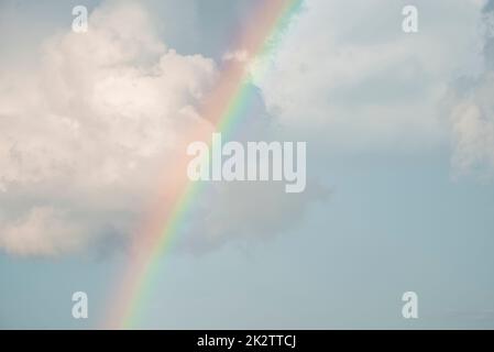 Idyllic view of rainbow amidst cloudy sky on sunny day Stock Photo