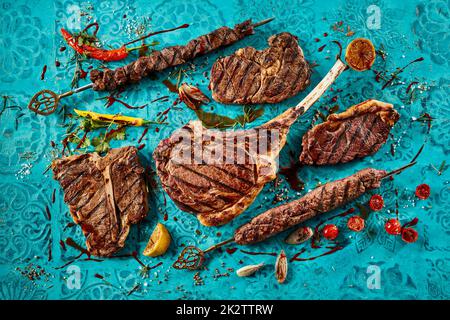 Grilled meat steaks placed on blue table Stock Photo