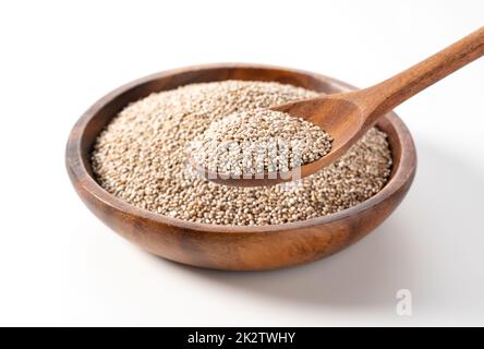White chia seeds in a wooden dish set against a white background and scooped up with a spoon. Stock Photo