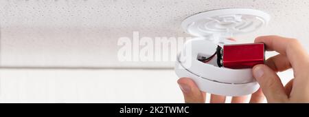 Person's Hand Inserting Battery In Smoke Detector Stock Photo