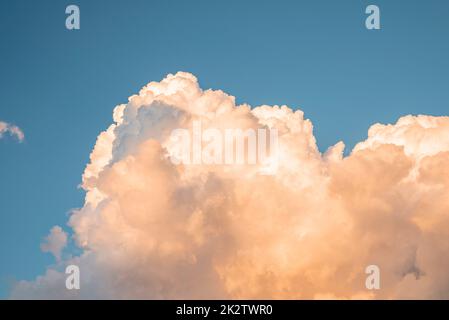 Scenic view of fluffy clouds covering blue sky during sunset Stock Photo