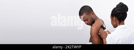 Doctor Examining Pigmented Skin On Man's Back Stock Photo