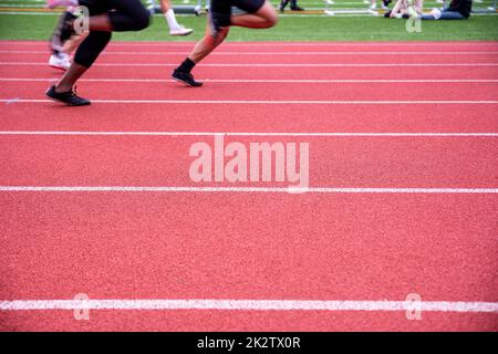 Two runners race on a red track and field athletic track with lane markers Stock Photo