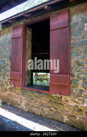 Colonial wagon seen through open stone barn window red shutters Stock Photo