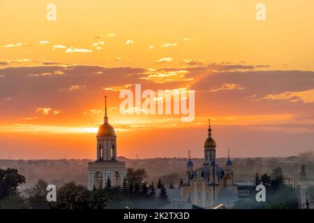 Golden domes with Orthodox crosses on the church.Temple or cathedral on the background of an evening sunset with a golden sky. A lonely church at dusk with sunset clouds.Golden Hour,skyline,horizon Stock Photo