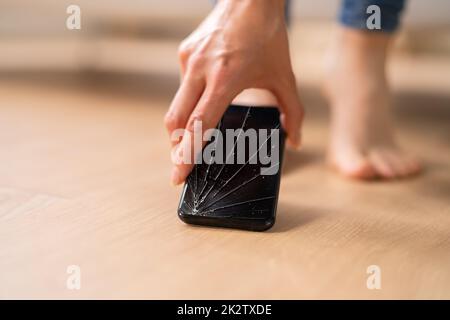 Woman Picking Up Damaged Mobile Phone Stock Photo