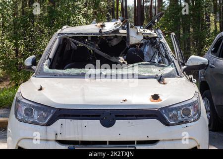 A car of civilians shot by the invaders during the war in Ukraine. Road accident or incident. Shrapnel holes in the body of the car. Atrocities of the Russian army. Ukraine, Irpen - May 12, 2022. Stock Photo