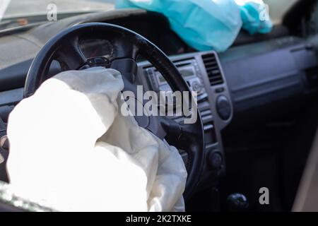 The driver's airbag deployed on the steering wheel of the car after the collision. Deflated airbags after flared deployment. The airbag deployed. Car after an accident. Safety device in the car. Stock Photo