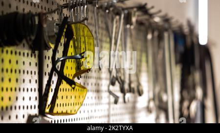 Goggles, various tools hanging on garage wall Stock Photo
