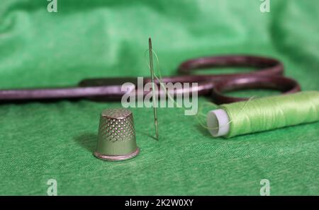 Spool of green thread and needle Stock Photo - Alamy