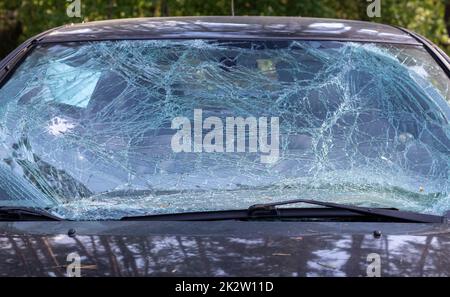 Close-up of a car with a broken windshield after a fatal crash. Consequence of a fatal car accident. Automobile danger. Reckless dangerous driving. Vehicle after an accident with a pedestrian. Stock Photo