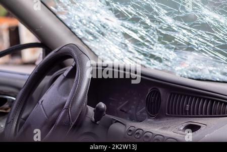 Close-up of the steering wheel of a car after an accident. The driver's airbags did not deploy. Soft focus. Broken windshield with steering wheel. Vehicle interior. Black dashboard and steering wheel. Stock Photo