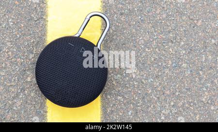 Waterproof round black Bluetooth speaker with carabiner. Digital music and audio concept. Mini, suitable for travel. Stock Photo